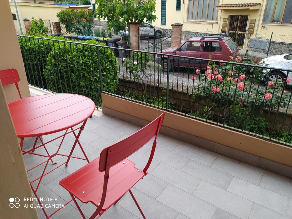 Terrazzo privato di Casa Palmira con tavolo e sedie rosse e rose in fiore